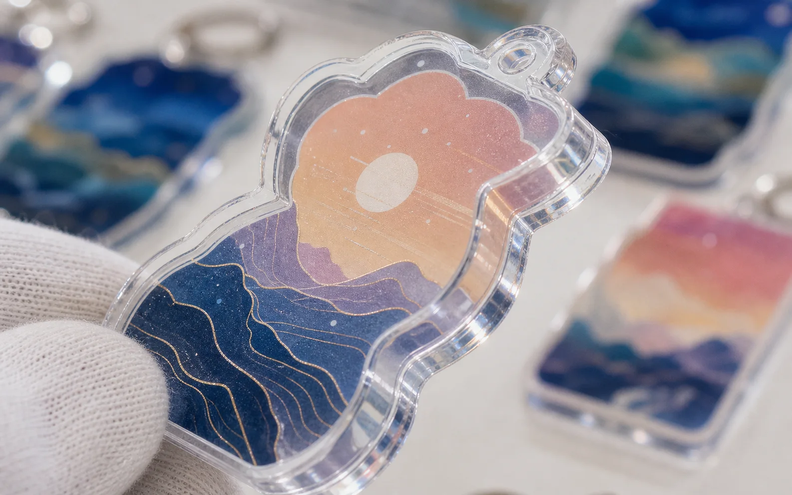 Close-up of a glitter-filled acrylic shaker charm with layered sunset artwork