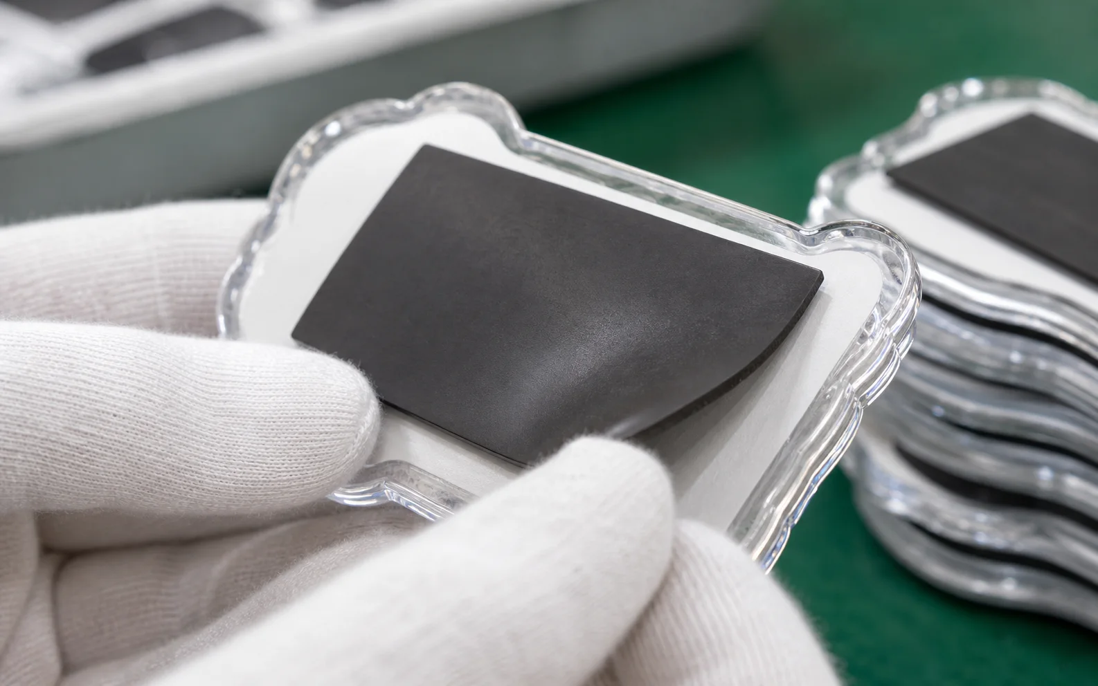 Gloved hand fitting a magnet disc onto the back of an acrylic piece