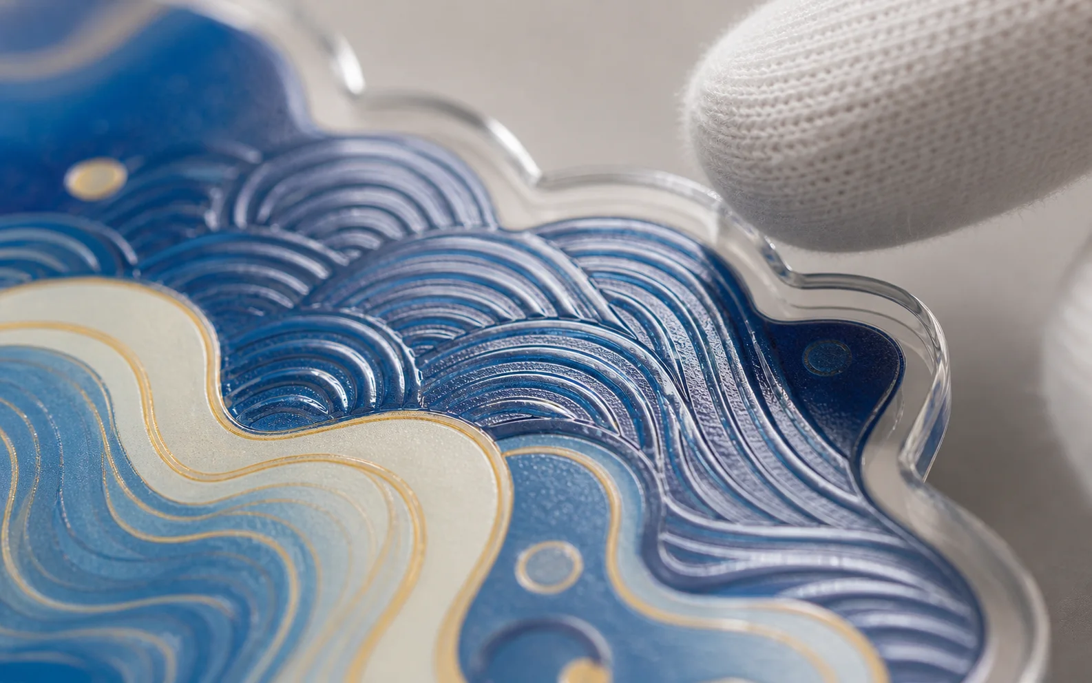 Close-up of a multi-layer acrylic charm with embossed wave artwork